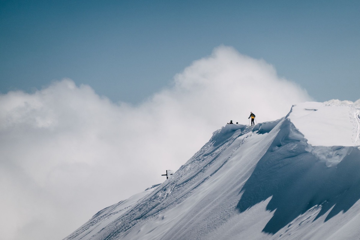 Um alpinista alcançando o topo de uma montanha, simbolizando a superação de metas.