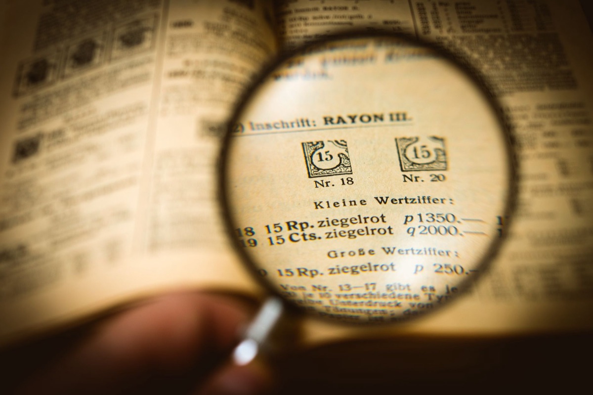 A magnifying glass laying on a contract, inspecting the fine print of a deal.