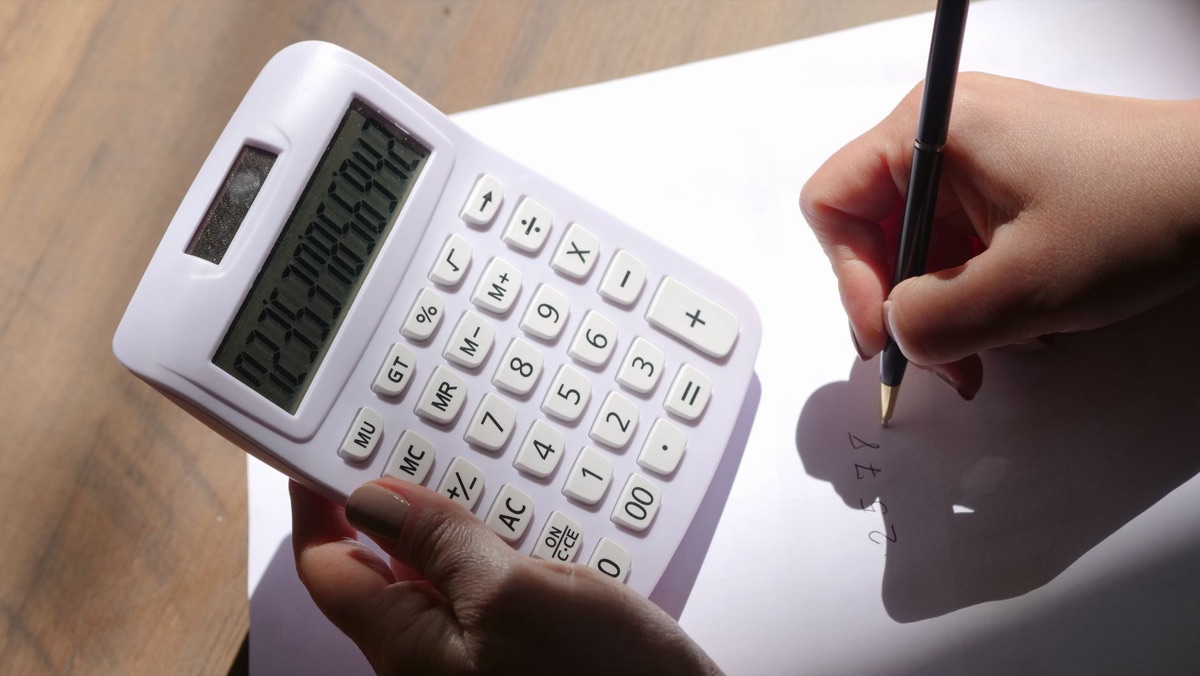 Une main tenant une calculatrice et un contrat pour une analyse de prix.