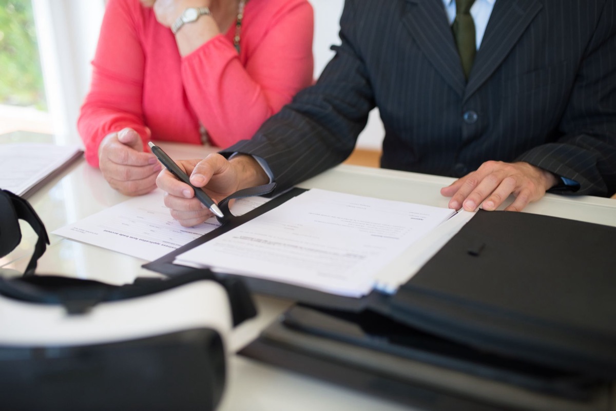 Dois profissionais discutindo detalhes de um contrato em uma mesa de escritório.