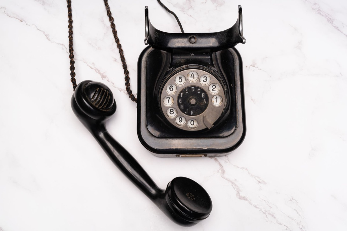 Vintage telephone receiver ringing on a dark wood surface, symbolizing an important incoming call.