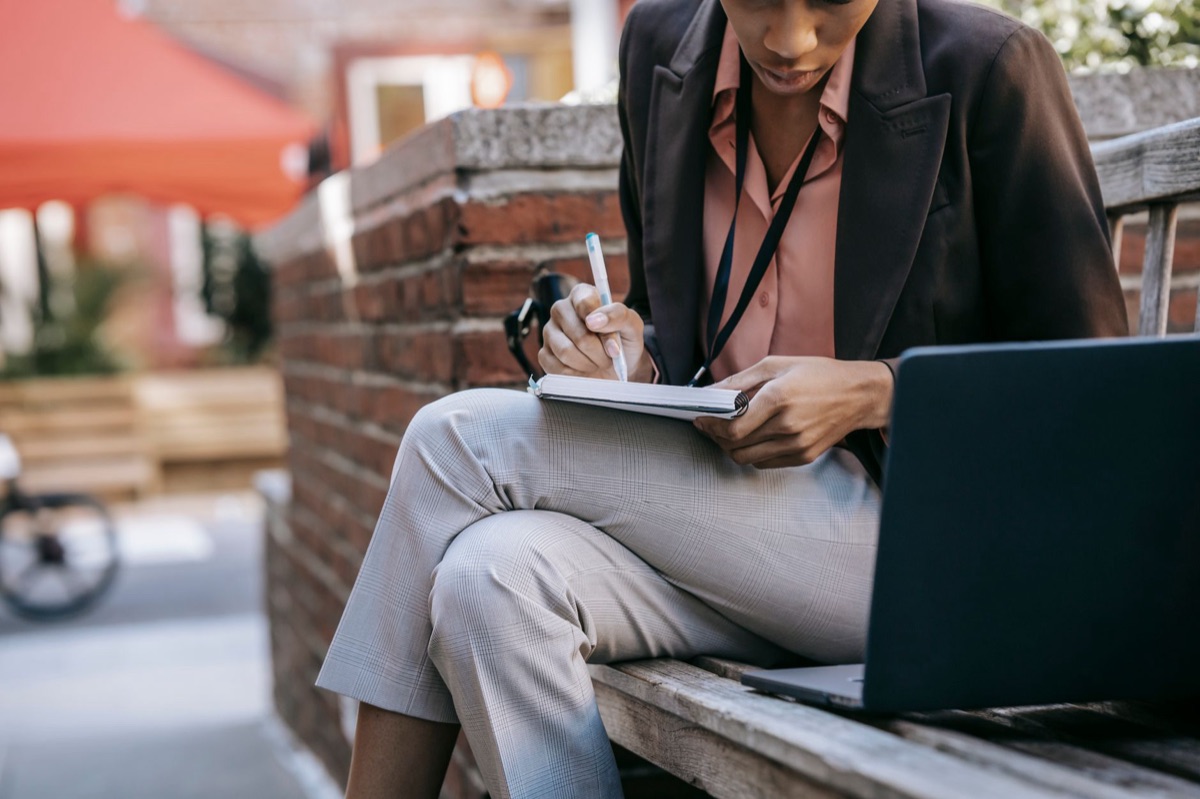 Salesperson with notebook and laptop preparing for presentation
